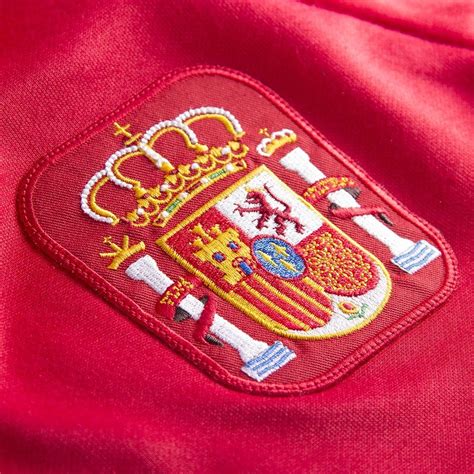 De versie van het shirt met korte rits uit het spaanse trainingstenue schittert met een teamembleem op de borst. Spanje Retro Voetbalshirt 1988 |Sportus.nl