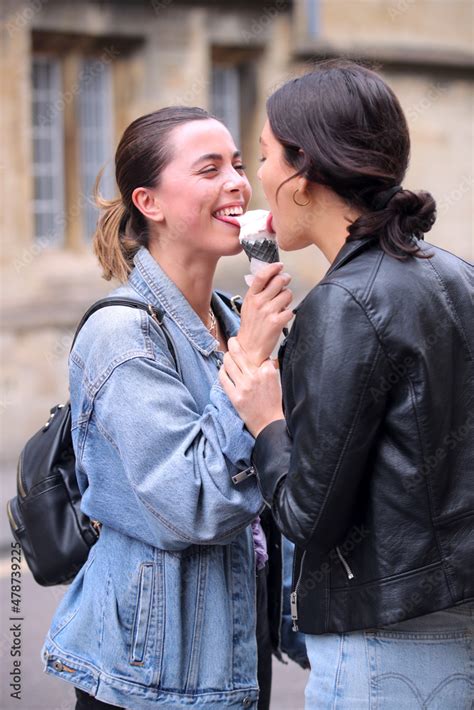 Same Sex Female Couple Sightseeing And Sharing Ice Cream As They Walk Around Oxford Uk Together