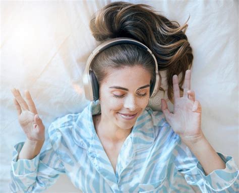 woman headphones and music listening in bed to relax at home podcast or radio streaming