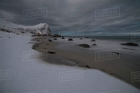 Moonlight Illuminates Snow Covered Beach At Myrland Flakstadøy