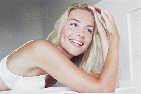 Portrait Of A Smiling Blonde Woman Lying On A Bed Stock Photo Dissolve