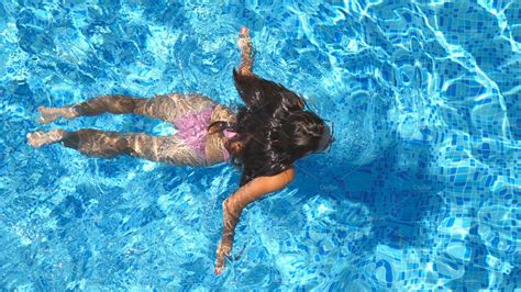 Unrecognizable Beautiful Girl Floating Across The Pool Of Hotel Young Woman Swimming In Clear