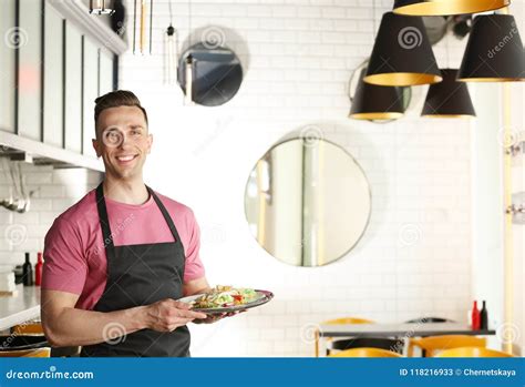 Young Waiter In Uniform Holding Tray With Tasty Dish Stock Image