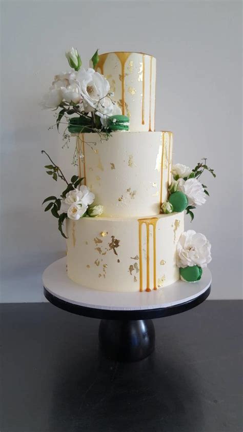 To add extra height to the art deco display, the entire dessert was suspended in the air on a swing made to resemble a glistening chandelier. Three tier buttercream with gold leaf, caramel sauce, green macarons and fresh white flowers ...