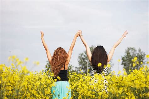 Beautiful Women Standing In A Field With Their Arms Outstretched Up In The Air Above Their