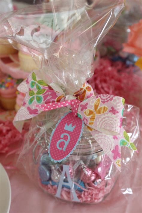 A Candy Jar Filled With Lots Of Candies On Top Of A Pink Table Cloth