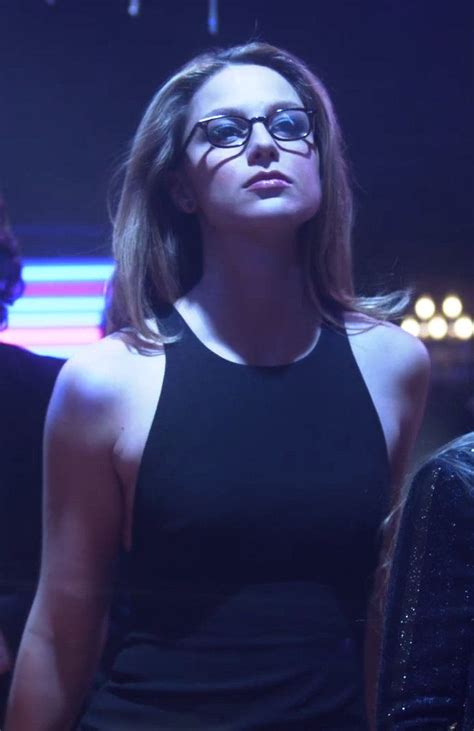 A Woman Wearing Glasses Standing In Front Of A Crowd At A Concert Or Show Looking Off Into The