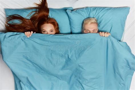 lusande kärleksfulla par som ligger i sängen under filt fotografering för bildbyråer bild av