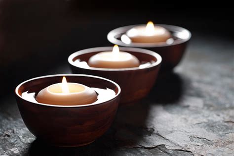 Three Lit Candles Floating In Wooden Bowls Filled With Water Stock