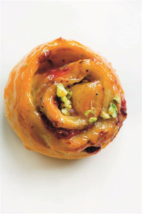 An Orange Pastry With Nuts And Other Toppings In It On A White Table Top