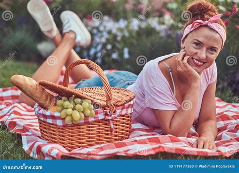 happy redhead middle age female in casual clothes with a headband enjoying during picnic