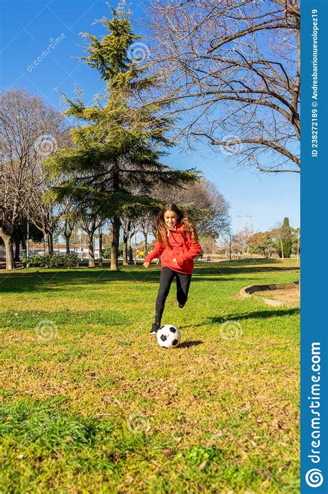 Pre Adolescent Girl Playing Soccer In A Park With Natural Grass