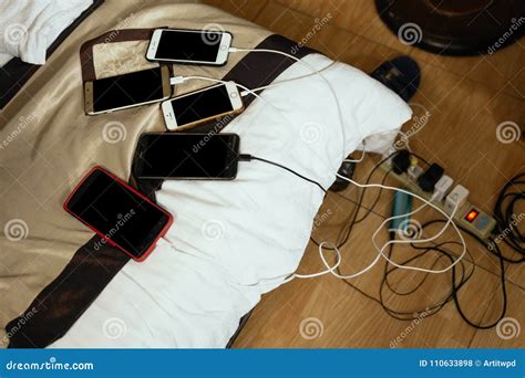 Charged Smart Phones On Bed With Charge Cords In A Mess At Hotel Room