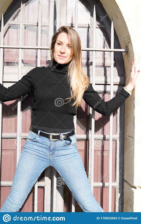 Confident Young Woman Posing Against Windows Ancient Wall Stock Image