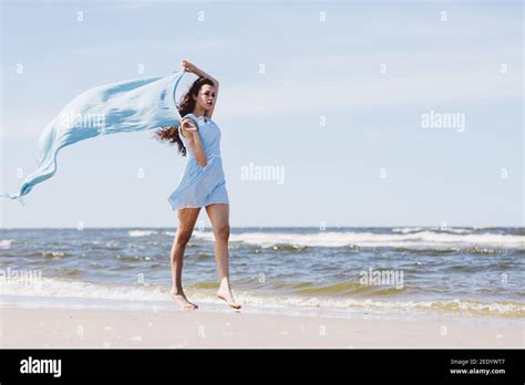 Pretty Girl Walking By The Sea With A Blue Waving Scarf Summer By The