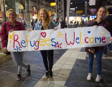three german girls welcome migrants with a heart warming sign in frankfurt refugees seek peace