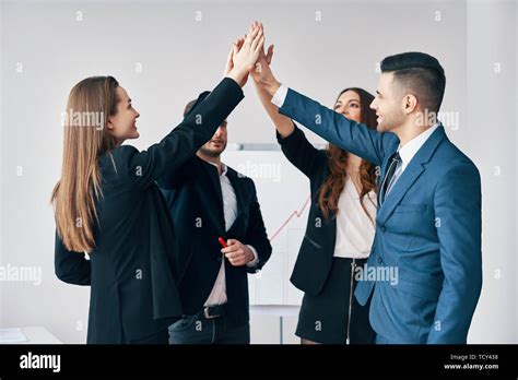 Smiling Young Business People Giving High Five To Each Other In Office