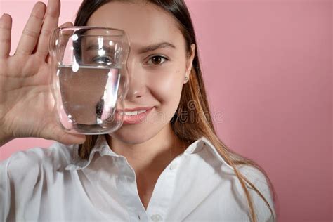 A Beautiful Young Brunette Holds A Glass Of Clean Water In Her Hands