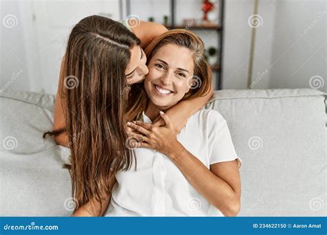 Mother And Daughter Kissing And Hugging Each Other Sitting On Sofa At