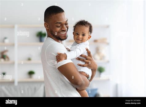 Happy African American Father Cuddling His Adorable Newborn Baby Son At