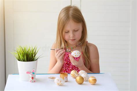 Little Girl Painting Eggs With Gold Paint Happy Easter Stock Photo