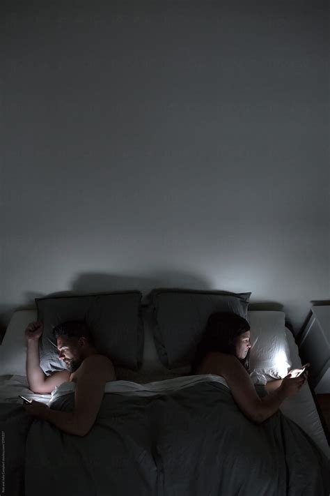 Couple Using Their Phones In Bed At Night By Stocksy Contributor Rob And Julia Campbell