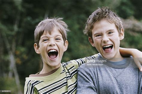 Portrait Of Two Young Boys Standing Side By Side Shouting And Pulling