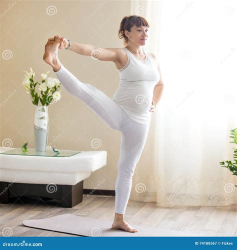 Pregnant Woman Doing Extended Hand To Big Toe Yoga Pose At Home Stock