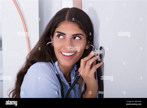 Young Curious Women Listening Through Wall Using Stethoscope Stock