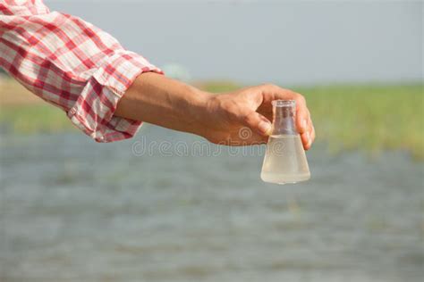 Water Purity Test Hand Holding Chemical Flask With Liquid Lake Or