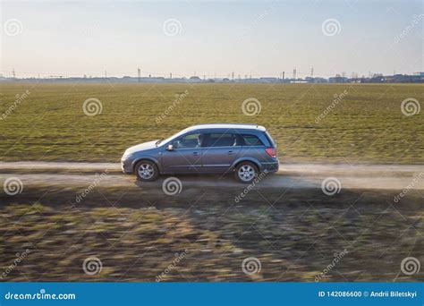 Aerial View Of Car Driving By Straight Ground Road Through Green Fields