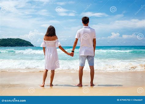 Back View Of Young Couple Standing On Sandy Beach Stock Photo Image