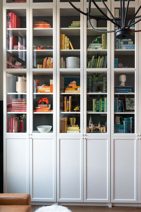 A White Bookcase Filled With Lots Of Books Next To A Light Hanging From