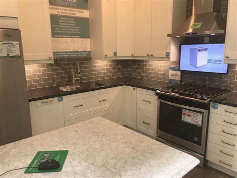 Kitchen display at Menards. White cupboards and a dark countertop with
