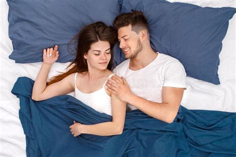 Bedtime Young Couple Lying On Bed Under Blanket Top View Hugging Waking Up Cheerful Stock Image