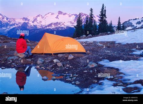 Woman Camps In Meadow With Mountain Backdrop In Whistler Alpine