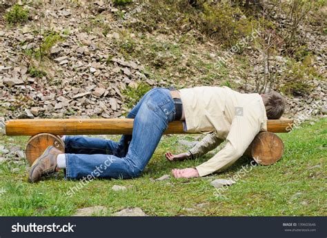 Young Man Deeply Sleeping Or Drunk Laying Outdoors On A Wooden Park