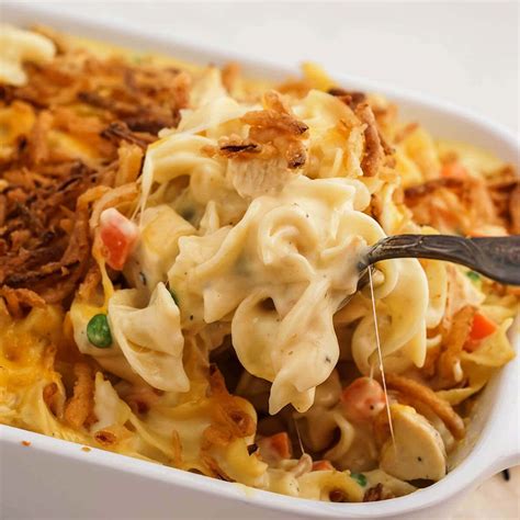 A Casserole Dish With Noodles Meat And Vegetables Being Spooned Into It