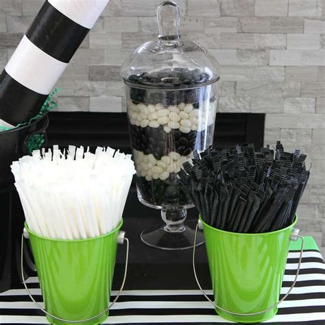 Two Green Buckets Filled With Black And White Candies On Top Of A Table