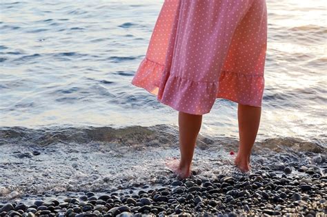 Premium Photo Womans Legs In Pink Dress Stand Barefoot In Water On