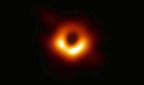 A Black Hole Is Seen In The Dark Sky With An Orange Ring Around It