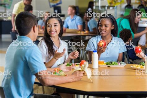 Male And Female Teenagers Enjoy Eating Lunch Together In The School