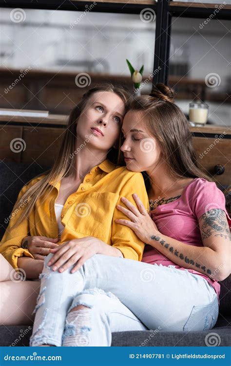 two pretty lesbians embracing while sitting on sofa in living room stock image image of