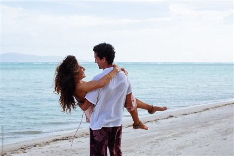 Man Carries A Girl In His Arms On The Beach Del Colaborador De