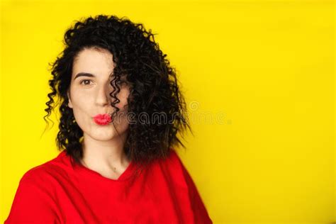 Charming Young Girl With Curly Black Hair In A Red T Shirt On A Yellow