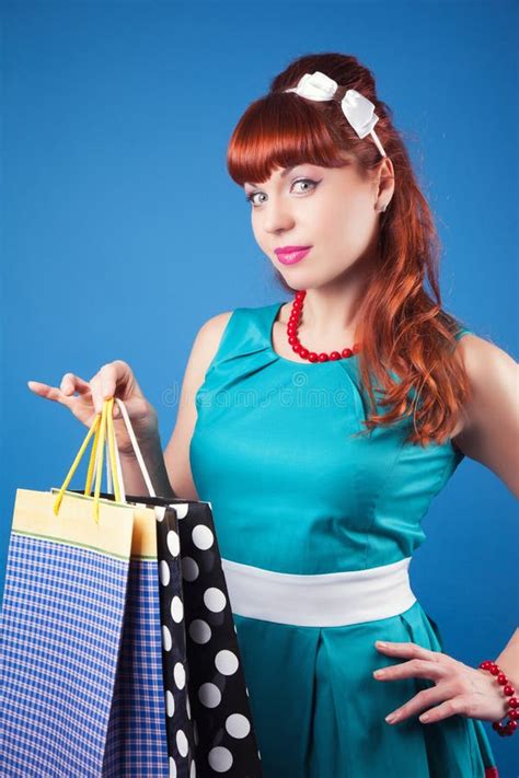 Beautiful Pin Up Girl Posing With Shopping Bags Against Blue Bac Stock
