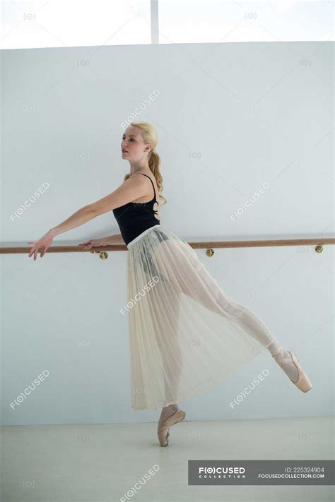 Ballerina Stretching On A Barre While Practicing Ballet Dance In The