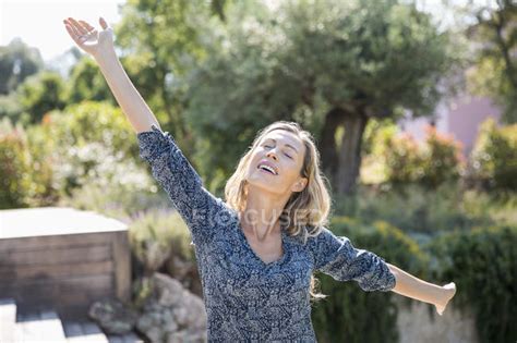 Happy Woman With Arms Outstretched Standing In Garden — Eyes Closed
