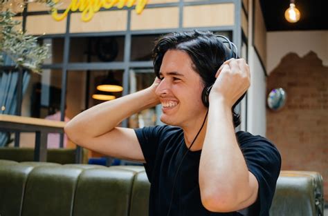 Niño Sonriente Escuchando Música Con Auriculares En Una Cafetería
