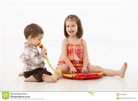 Entzückende kleine junge und süße kleine mädchen haben eine kissenschlacht im sonnigen wohnzimmer. Kleine Kinder, Die Mit Spielzeuginstrument Spielen ...